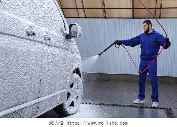 正在洗车的汽修工人洗车时用泡沫覆盖汽车的工人